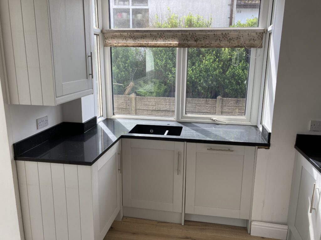 Finished sink run with dark worktops and composite sink under the kitchen window